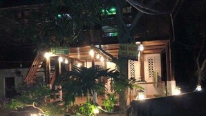 A small, dimly lit building with a sign that reads "NHÃN NGHI" and a staircase leading to the entrance.