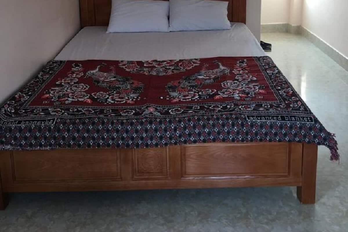 A bedroom with a wooden bed, white pillows, and a red patterned blanket.