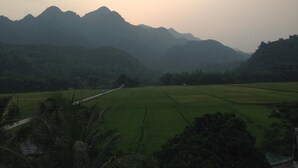 A rural landscape with green fields and mountains in the background.
