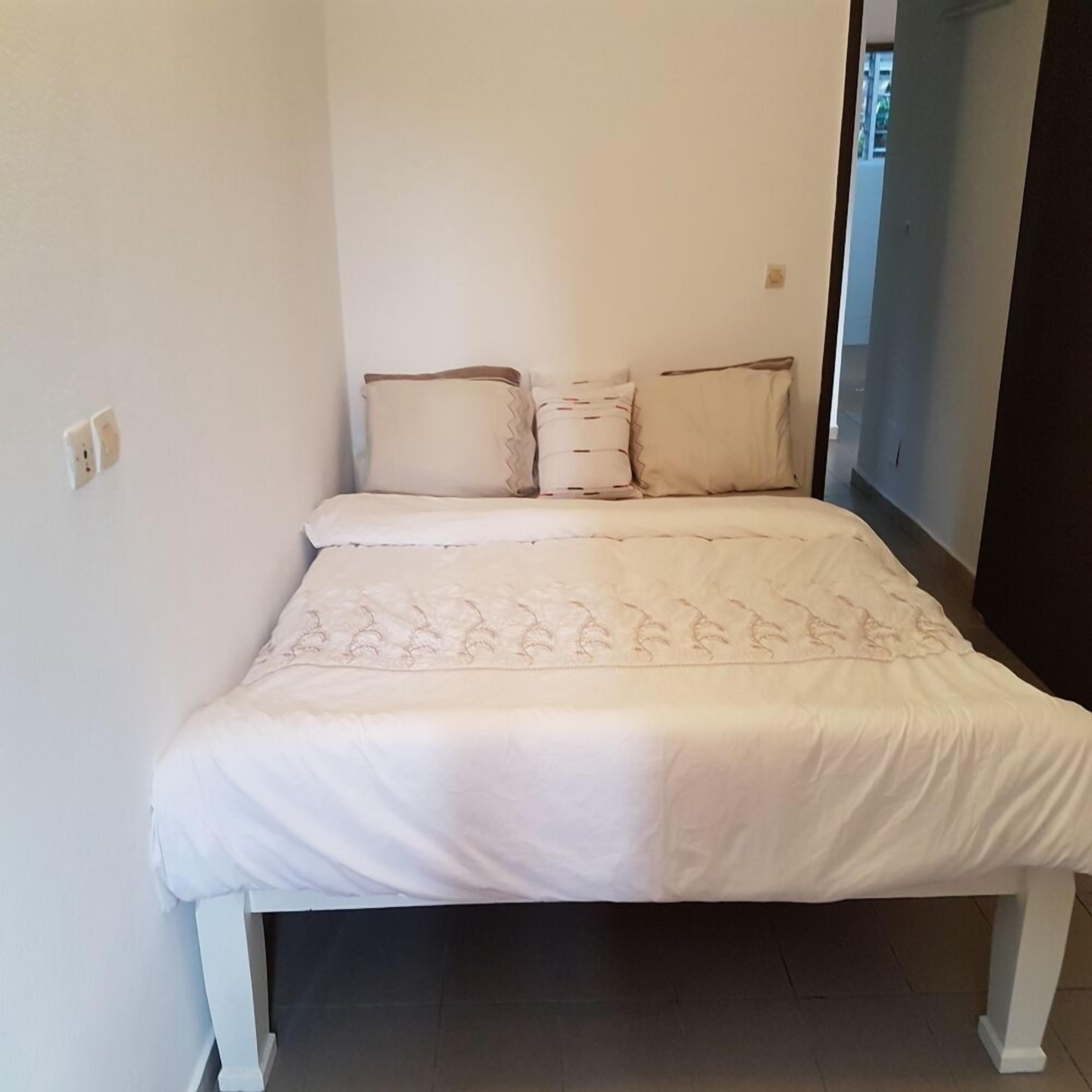 A small, single-bed room with a white bedspread and matching pillows.
