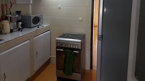 A compact kitchen with a microwave, stove, and refrigerator. - Résidence Marié Majeur (Abidjan)