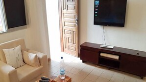 A living room with a sofa, a coffee table, a TV, and a wooden cabinet. - Résidence Marié Majeur (Abidjan)