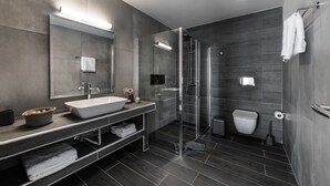A modern bathroom with a large sink, mirror, and walk-in shower. - Santorini Main Square (Santorini)