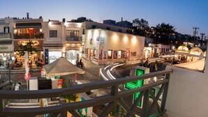 A bustling urban square with multiple shops and cafes, a prominent hairdresser, and a central open area with seating. - Santorini Main Square (Santorini)