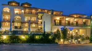 A multi-story hotel with balconies, a central staircase, and a well-lit facade. - Leandros Hotel (Aristotelis)