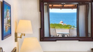 A room with a view of the ocean, a table, two lamps, and a painting on the wall. - Leandros Hotel (Aristotelis)