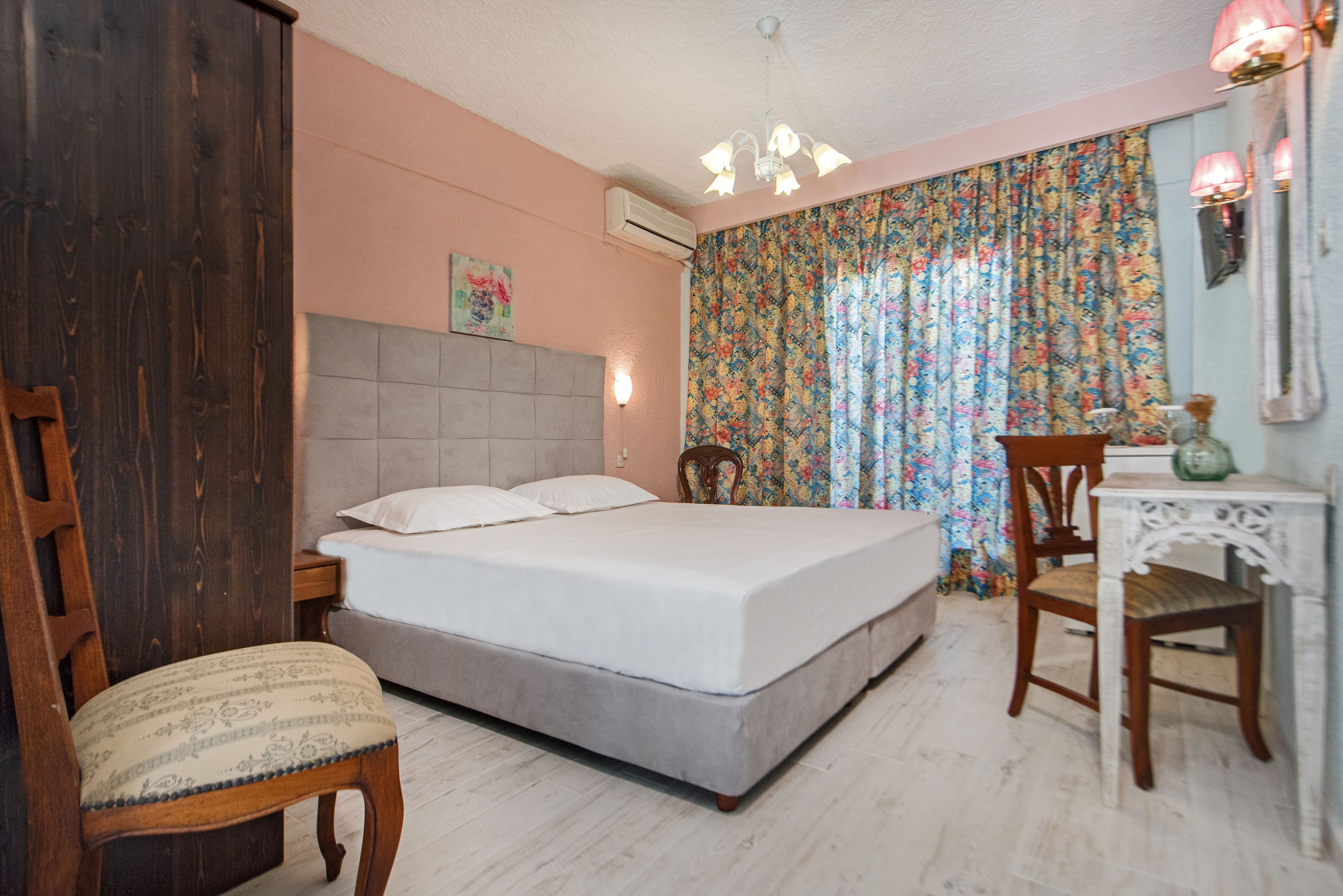 A bedroom with a bed, a chair, a small table, and a decorative lamp.
