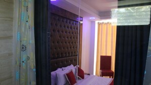 Quarto de hotel com uma cama grande, uma cadeira vermelha e um espelho.