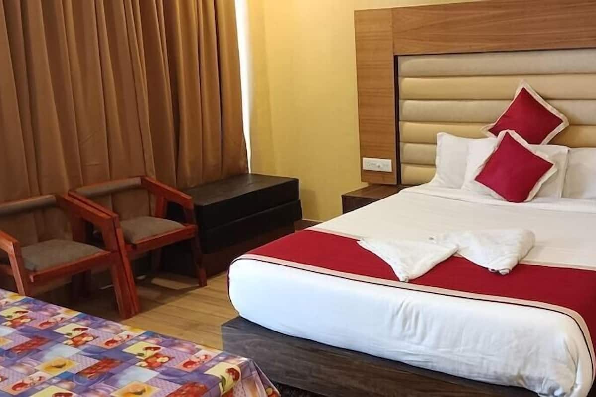 A hotel room with a bed, a chair, a small table, and a nightstand.