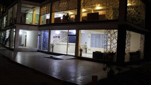 Hotel com área de recepção, portas de vidro e fachada estampada.