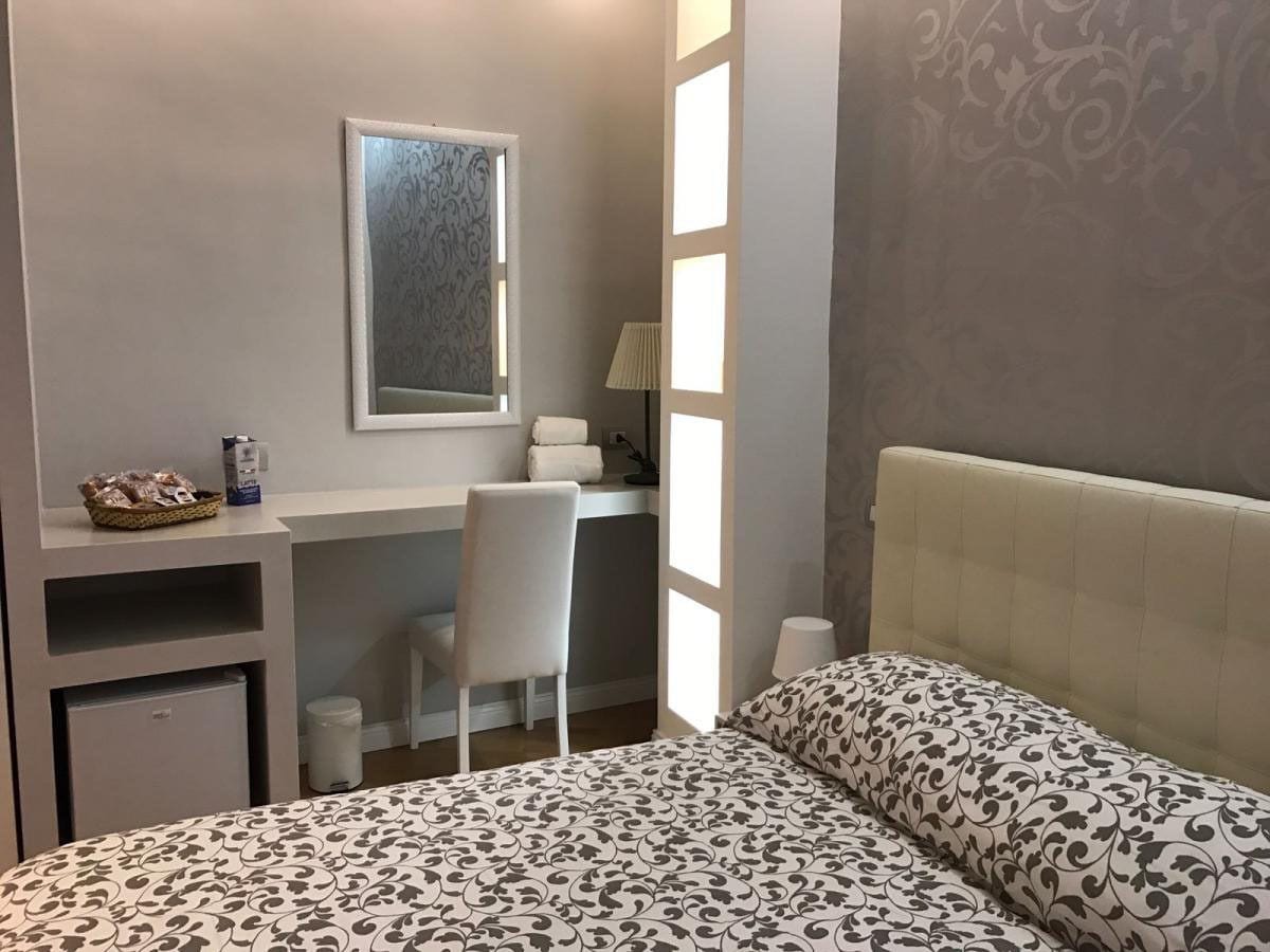 Un dormitorio con cama, escritorio y silla. Hay una ventana que deja entrar luz natural.