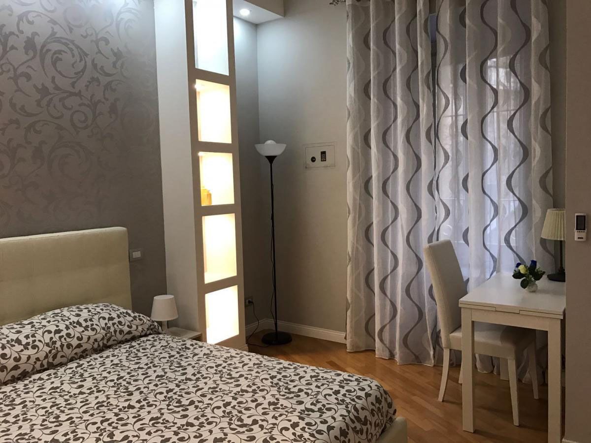 Un dormitorio con cama, escritorio, silla, lámpara de pie y ventana con cortinas.
