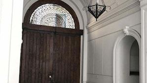 Una imponente entrada con una puerta de madera grande, piso a cuadros y una escalera que lleva a un nivel superior.