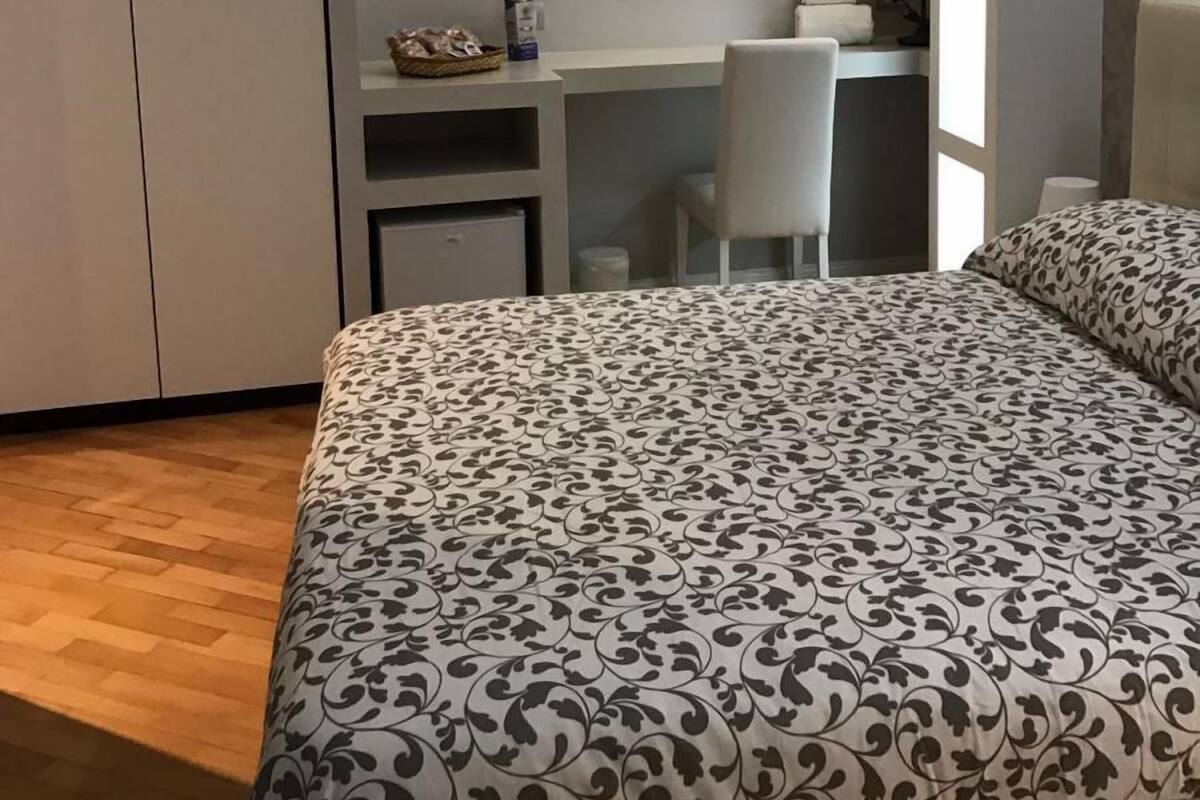 A bedroom with a bed, a desk, and a chair.