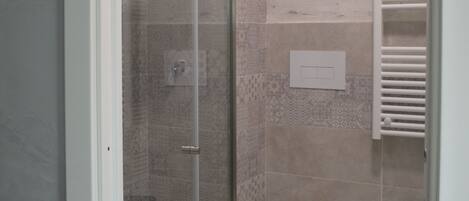 Un baño con cabina de ducha de vidrio, inodoro y bidé.