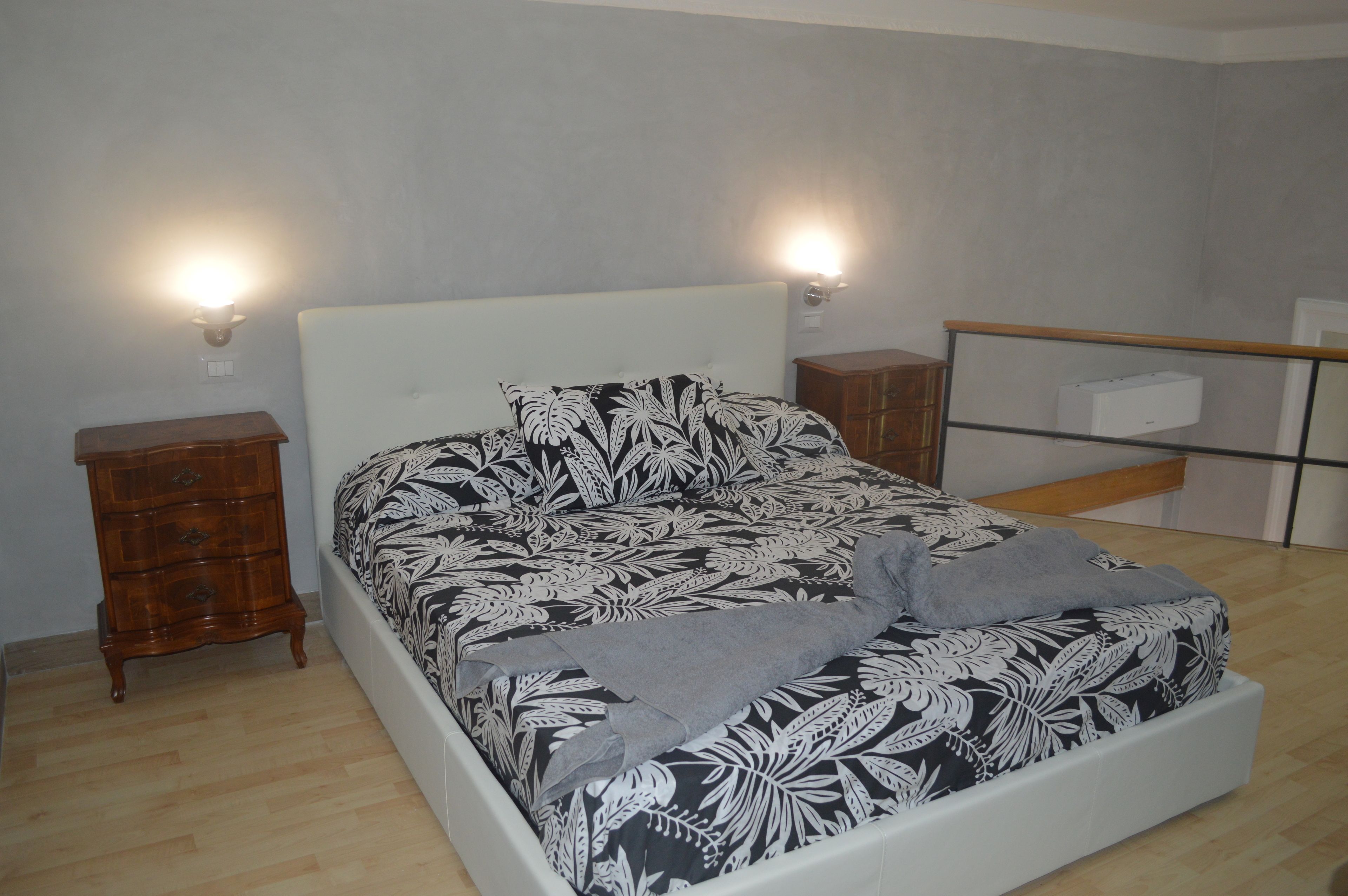 A bedroom with a bed, two nightstands, a dresser, and a mirror.