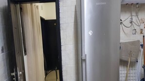 A kitchen with a refrigerator, stove, and a door leading to another room. - Résidence Olivier (Abidjan)