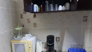 A kitchen with a microwave, toaster, coffee maker, and a blue tray. - Résidence Olivier (Abidjan)