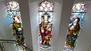 A staircase with three stained glass windows depicting religious figures. - Inversnaid Bunkhouse - Hostel (Arrochar)