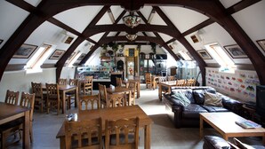 A spacious loft with high ceilings, wooden beams, and a cozy seating area. - Inversnaid Bunkhouse - Hostel (Arrochar)