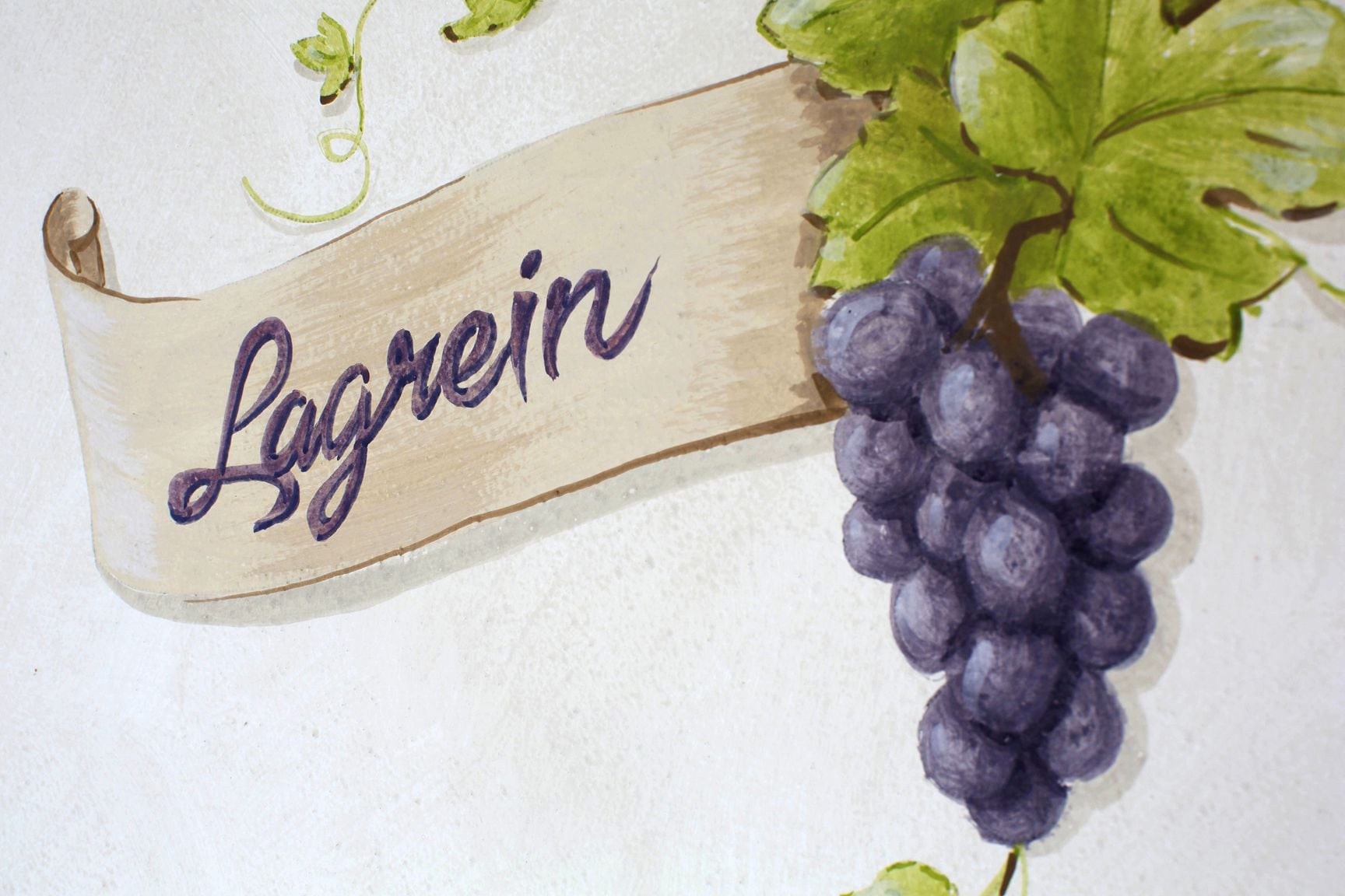 Un letrero de madera con la palabra 'Lagrein' y un racimo de uvas.