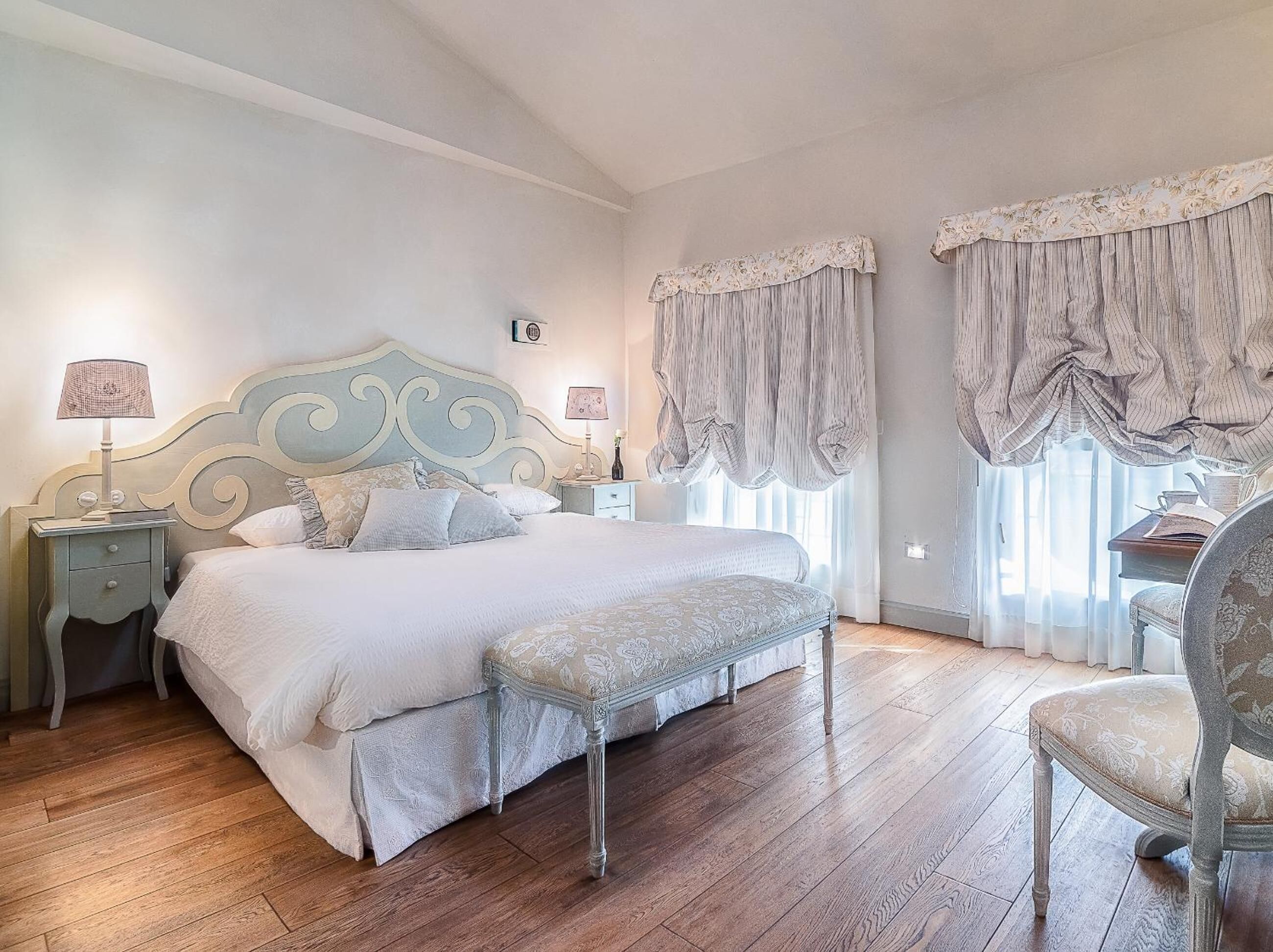Une chambre à coucher avec un grand lit, deux tables de chevet, une chaise et un bureau.