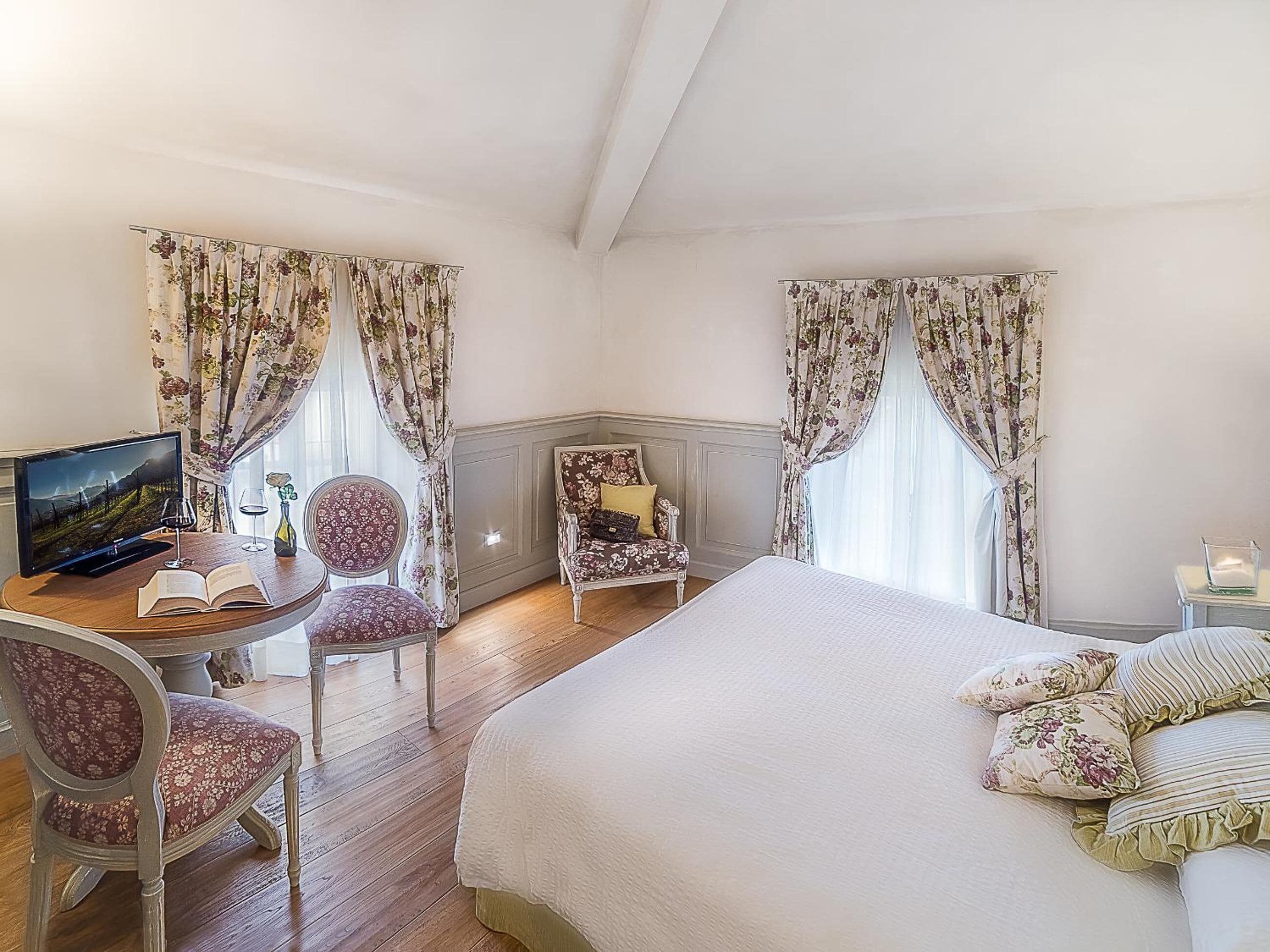A room with a bed, a desk with a computer, a chair, and a window with curtains.