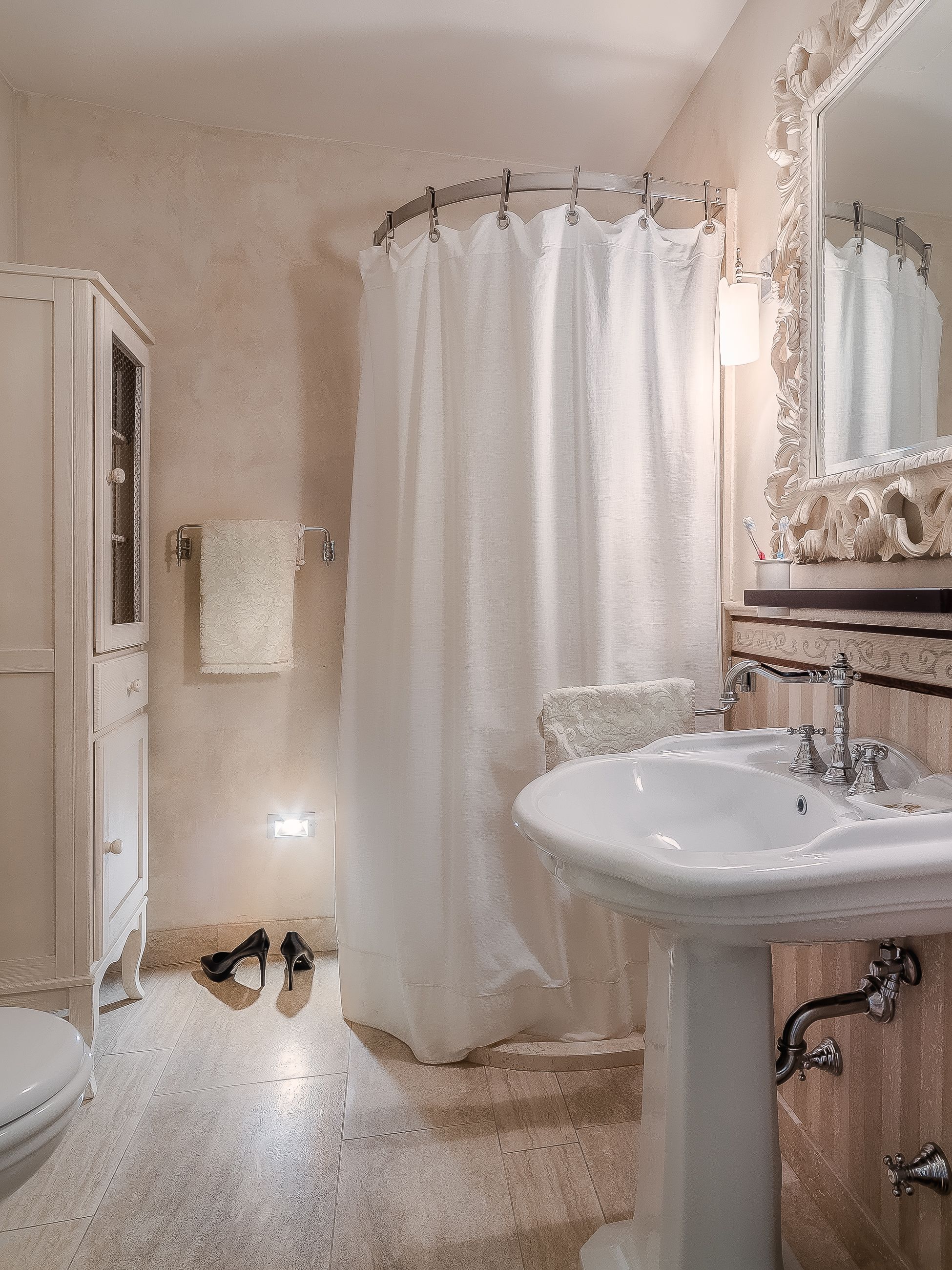 A bathroom with a white sink, a mirror with an ornate frame, and a shower curtain.