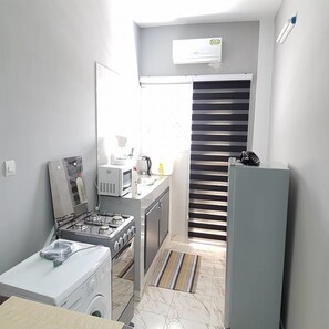 Una cucina compatta con piano cottura a gas, forno a microonde e frigorifero.