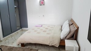 A bedroom with a bed, a nightstand, a lamp, and a wardrobe.