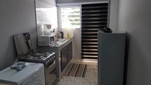 A compact kitchen with a gas stove, microwave, coffee maker, and a refrigerator.