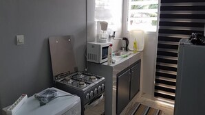A compact kitchen with a gas stove, microwave, sink, and a washing machine.