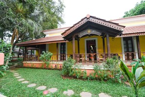 Traditional building with a central entrance, balcony, and beautifully maintained garden.