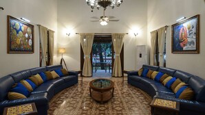 Un salon avec deux canapés bleus, une table basse, une moquette à motifs et des œuvres d’art accrochées aux murs.