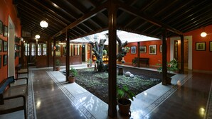 Une cour intérieure abritée, avec un jardin central, des bancs et des plantes en pot.