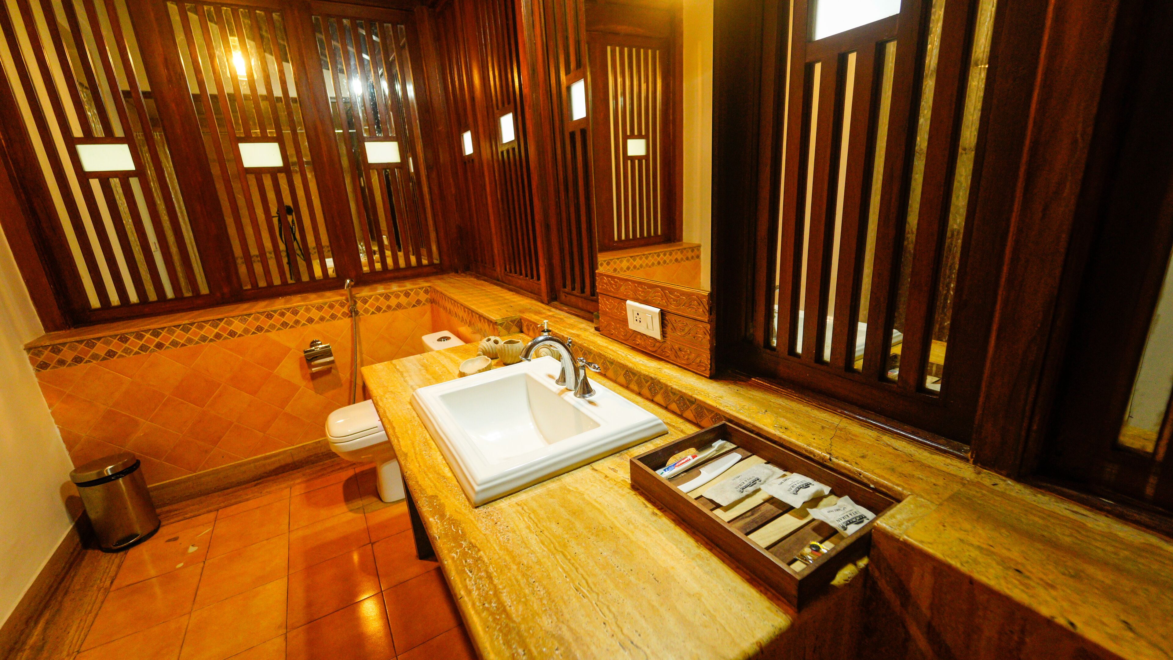 Ein Badezimmer mit Waschbecken, Toilette und Dusche. Ein Holzwaschtisch mit Spiegel und einer Ablage für Toilettenartikel.