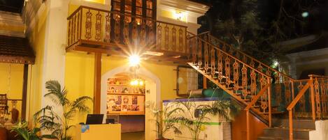 Ein Hotel Eingangsbereich mit Empfangstresen, Zimmerpflanzen und einer Treppe zum Obergeschoss.