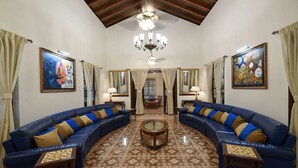 Un salon avec deux canapés bleus, une table basse au centre, une moquette à motifs et des œuvres d’art accrochées aux murs.