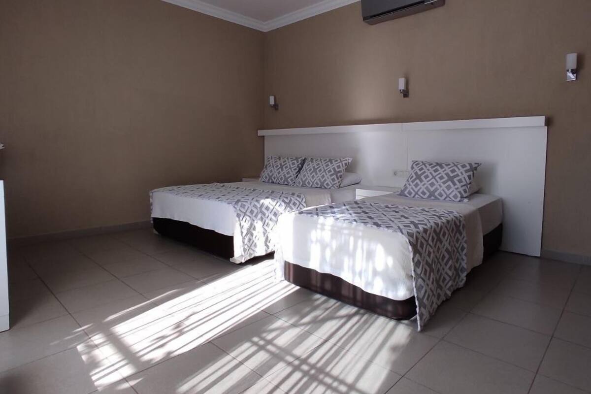 A bedroom with two beds, a white ceiling fan, and a wall-mounted air conditioner.