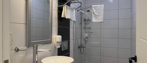 Et moderne badeværelse med en hvid vask, et spejl og et bruseområde.
