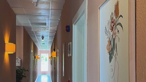 Un pasillo de hotel con suelo de baldosas, lámparas en la pared y un letrero de salida de incendios.