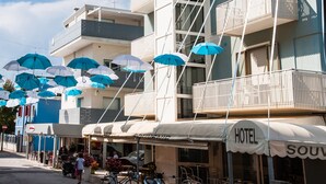 A hotel with multiple balconies, outdoor seating, and a sign indicating it is a hotel. - Hotel Souvenir (Caorle)