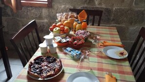 Una mesa de comedor dispuesta con diversos alimentos, incluyendo una tarta, frutas y salsas.
