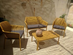 A set of yellow wicker chairs with grey cushions, arranged around a small round table with a vase. - B&B La Casetta (Cavallino)
