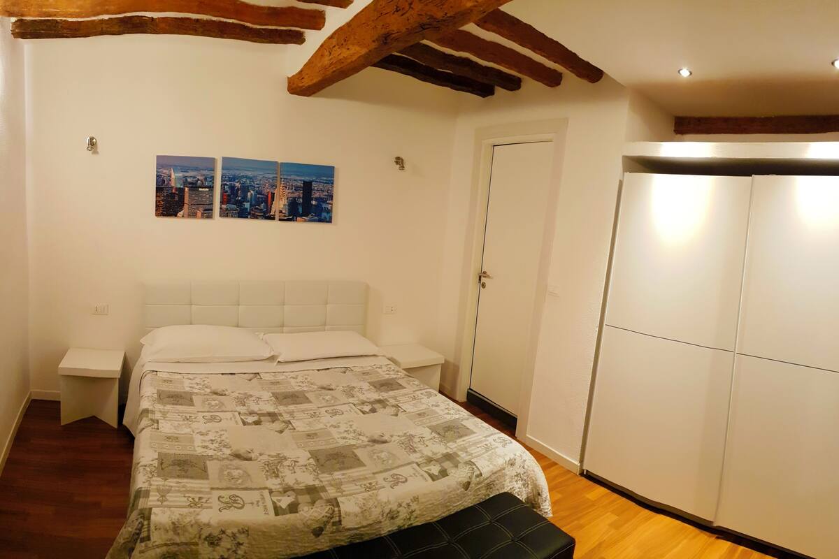Une chambre à coucher avec un lit, une armoire et deux tableaux représentant des paysages urbains accrochés au mur.