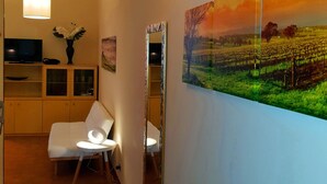 A hallway with a modern interior, including a white sofa, a television, and a large framed landscape painting. - Mosaico Aparthotel (Modena)