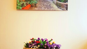 A room with a painting of a garden pathway and a floral arrangement on a table. - Mosaico Aparthotel (Modena)