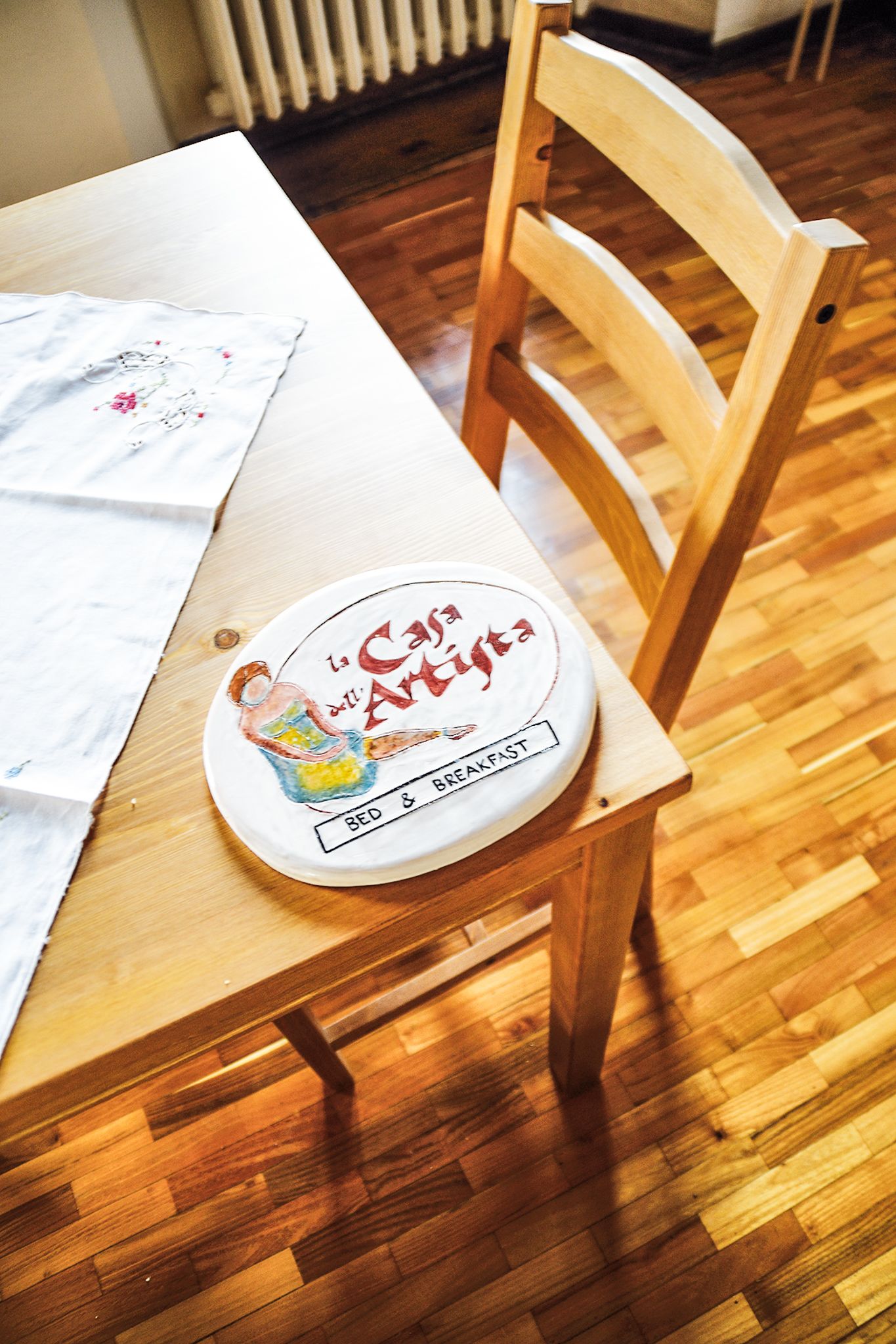 Un tavolo da pranzo in legno con tovaglietta bianca e un piatto con la scritta "La Casa de Arte y Arte".