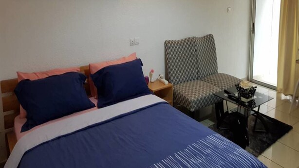 A hotel room with a bed, a chair, a small table, and a wall-mounted picture of the moon phases. - Residence Fatny (Abidjan)