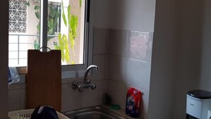 A kitchen with a sink, a window, and a coffee maker on the counter. - Residence Fatny (Abidjan)